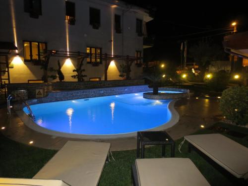 a large blue swimming pool in a yard at night at Hotel Due Torri in Agerola