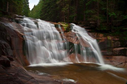 a waterfall on the side of a rock cliff at Pension & Restaurant Krakonoš in Harrachov