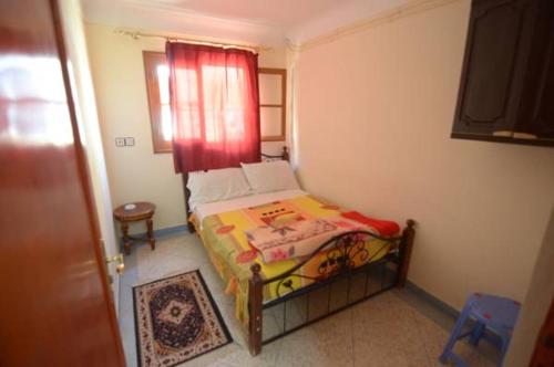 um pequeno quarto com uma cama com uma cortina vermelha em Hotel Imilchil em Zaouia ech Cheïkh