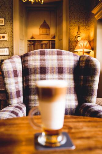 a cup of coffee sitting on a table with a couch at Causeway Hotel in Bushmills