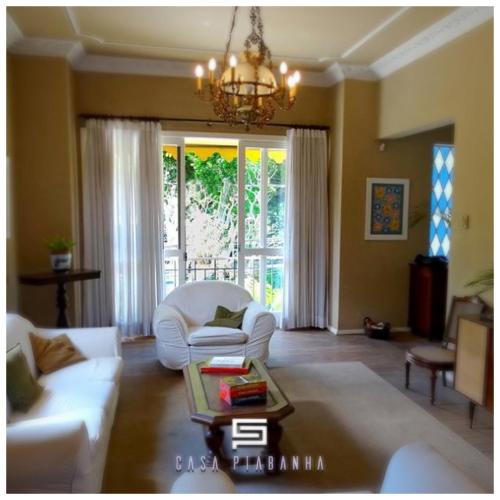 a living room with a white couch and a chandelier at Casa Piabanha - Centro Histórico in Petrópolis