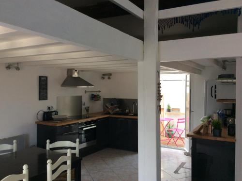 een keuken met zwarte kasten en een tafel en stoelen bij Maison Banyuls in Banyuls-sur-Mer