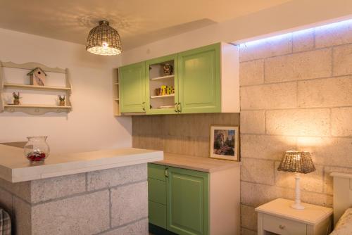 a kitchen with green cabinets and a lamp at Apartments Rakuljic in Podstrana