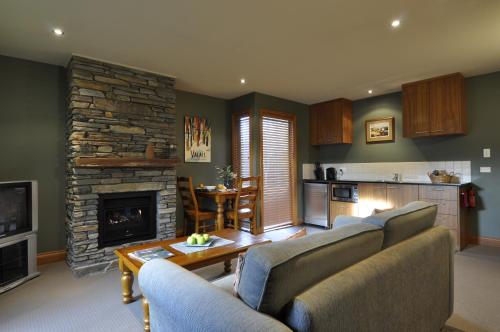 un soggiorno con 2 divani e un camino in pietra di Lansdown Peaks Apartments a Wanaka