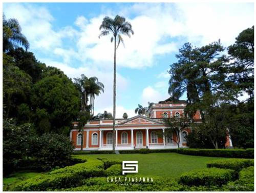 a large house with a palm tree in front of it at Casa Piabanha - Centro Histórico in Petrópolis
