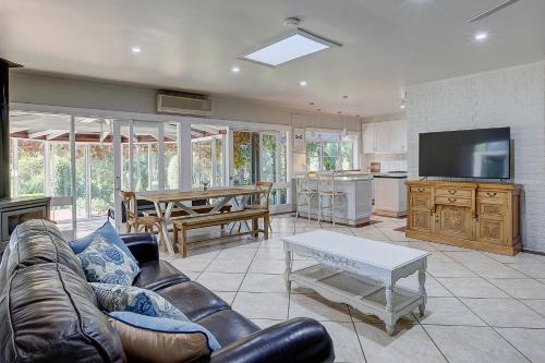 a living room with a leather couch and a table at Evanslea Luxury Boutique Accommodation in Mudgee