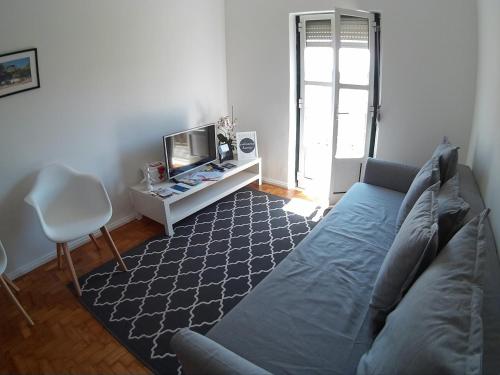 a living room with a blue couch and a tv at Olival 178 in Lisbon