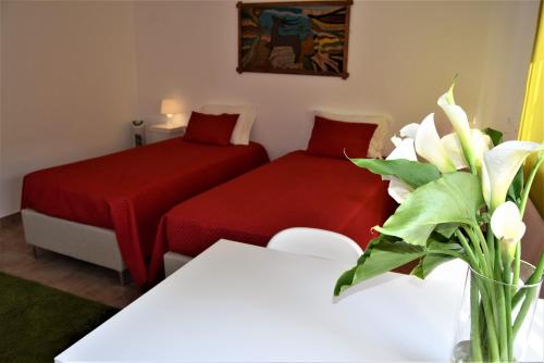 ラゴスにあるAurora Housesのベッド2台、花瓶付きのテーブルが備わる客室です。