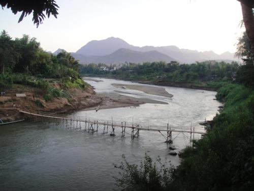 a bridge over a river with mountains in the background at Luang Prabang Nagara Villa River View in Luang Prabang