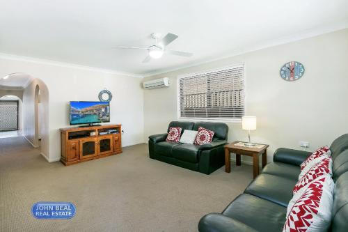 a living room with a couch and a tv at Beachside Holiday Home in Redcliffe