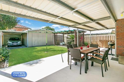 a patio with a wooden pergola and a table and chairs at Beachside Holiday Home in Redcliffe