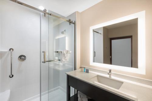 a bathroom with a sink and a shower with a mirror at Wingate by Wyndham Lubbock in Lubbock