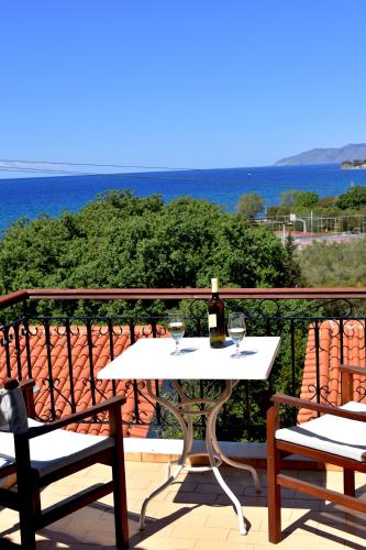 a white table with two glasses of wine on a balcony at Delfinia Hotel & Bungalows in Mithymna