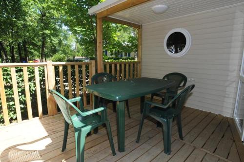 une table et des chaises vertes sur une terrasse dans l'établissement Camping Hurongues, à Pomeys