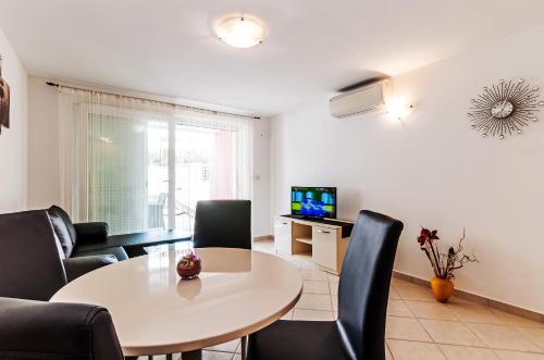 a living room with a table and chairs and a television at Villa Pino with Pool, Sauna & Jacuzzi in Petrcane