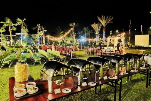 a table with food on it with chairs and lights at MaxOneHotels at Resort Makassar in Makassar