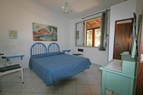 a bedroom with a blue bed and a desk and a window at Baglio Del Sole in San Vito lo Capo