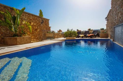 a large blue swimming pool next to a building at Carini Farmhouses in Għarb