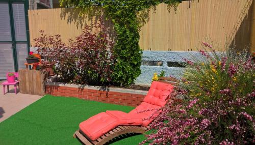 a red bench in a garden with flowers and plants at Crazy House Hostel in Pula