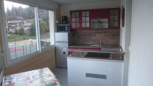 uma cozinha com armários vermelhos e um frigorífico branco em La Serre Nelly Philippe em Prémanon