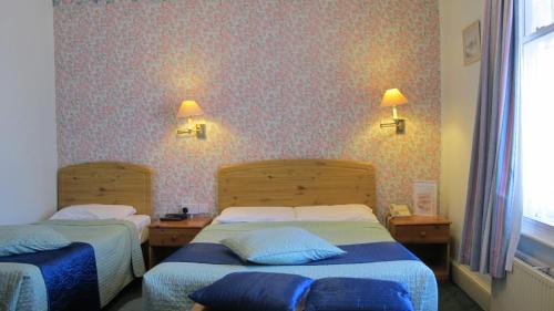 two beds in a hotel room with two lamps on the wall at River Hotel in Oxford
