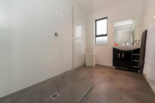a white bathroom with a sink and a mirror at Trendy Bungalow in the Heart of Rotorua in Rotorua