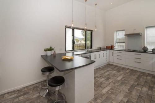 a kitchen with white cabinets and a black counter top at Trendy Bungalow in the Heart of Rotorua in Rotorua
