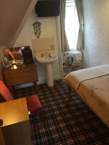 a small bedroom with a bed and a sink and a sink at Tanglin Guest House in Oban