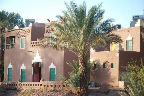 a building with a palm tree in front of it at d'hôte Jnane-Dar Diafa in Tamegroute