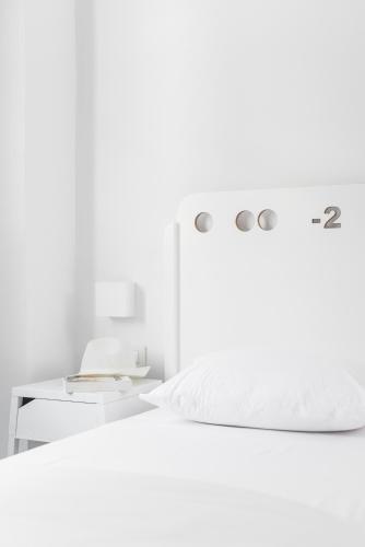 a white bedroom with a bed and a table at Cocoon City Hostel in Chania Town