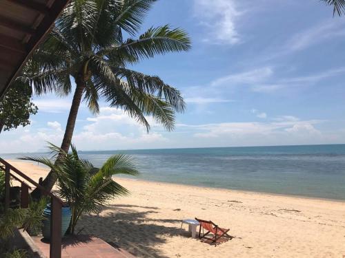 a beach with a chair and a palm tree at Bangpo Village in Ban Bang Po