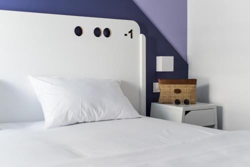 a white bed with a white pillow and a blue wall at Cocoon City Hostel in Chania Town
