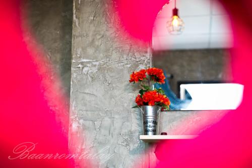 un jarrón con flores rojas sentado en un estante en Baan Rom Talay, en Ko Samed