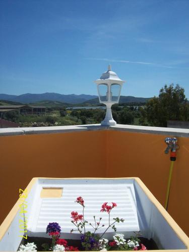a light on a balcony with flowers in a planter at Domos Le Due Tuie in Piscinas