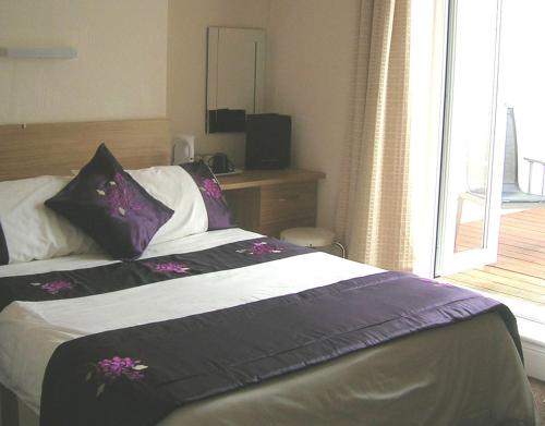 um quarto com uma cama com almofadas roxas e brancas em Harrington Guest House em Newquay