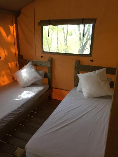 deux lits dans une petite pièce avec une fenêtre dans l'établissement Camping du Puy Rond, à Bressuire