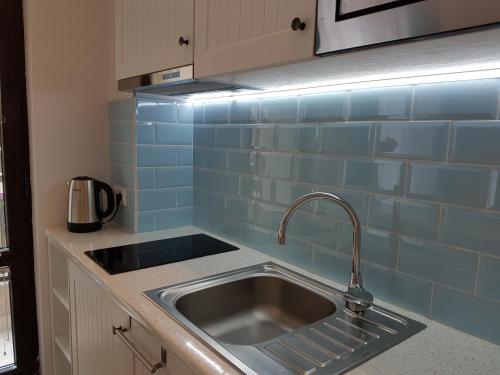 ポモリエにあるBlack Sea Apartmentの青いタイル張りの壁、シンク付きのキッチンが備わります。