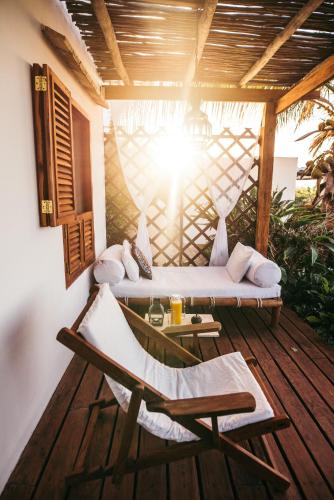 a porch with a bed and a chair on a deck at Baia Sonambula in Praia do Tofo