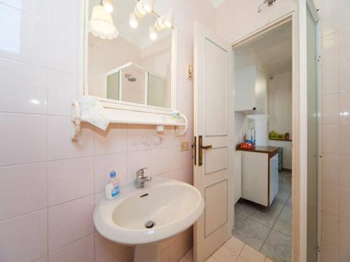 La salle de bains blanche est pourvue d'un lavabo et d'un miroir. dans l'établissement Appartamento il Panorama, à Ischia