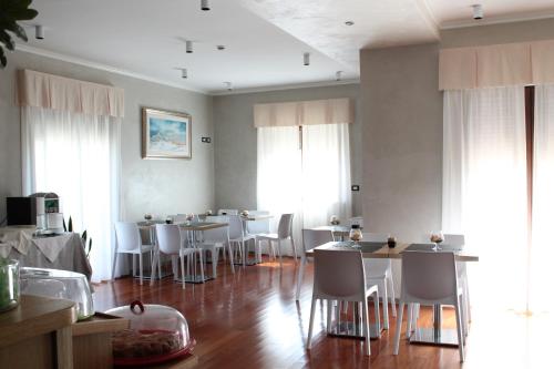 a dining room with tables and white chairs at Halanus Hotel And Resort in Alanno