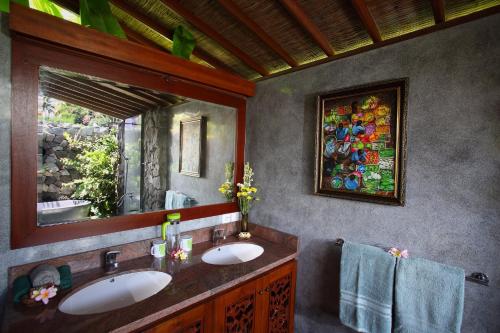 a bathroom with two sinks and a large mirror at Satori Villas Bali in Ubud