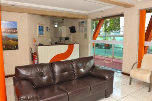 a living room with a leather couch and a kitchen at Pousada Águas do Forte in Cabo Frio