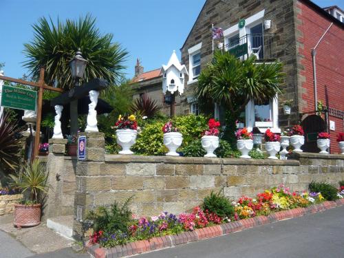 a retaining wall with many flower pots on it at White Owl Holiday Apartments in Robin Hood's Bay