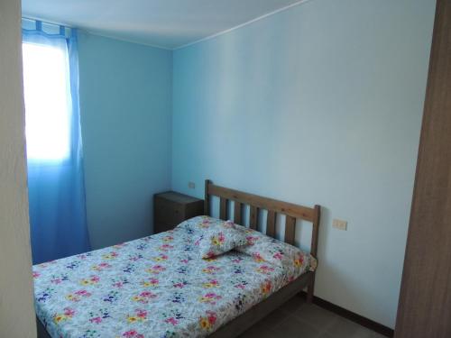 a small bed in a room with a blue wall at Appartamenti Camping Rivamare in Albenga