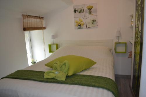 a green stuffed animal sitting on top of a bed at Maison Sous Le Pont in Meyras