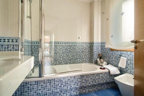a blue tiled bathroom with a tub and a sink at Pontus Veteris in Sanxenxo