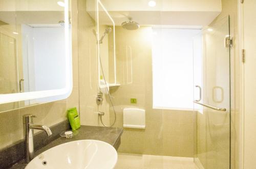 a bathroom with a sink and a shower at MaxOneHotels at Resort Makassar in Makassar