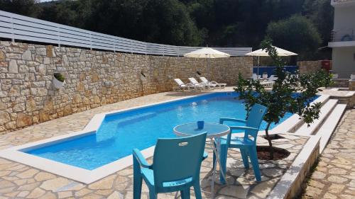 a swimming pool with blue chairs and a table and a table and chairsitures at La Sirenetta Residence in Sivota