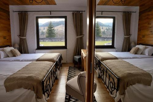 a bedroom with two beds and two windows at Bio Valeputna in Valea Putnei