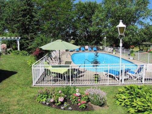 einen Pool mit Sonnenschirm, Stühlen und Blumen in der Unterkunft Green Acres Inn in Kingston